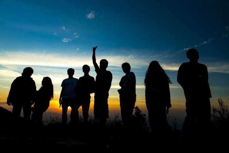 Youth group gathered outdoors at sunset for praise and worship