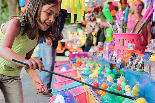 A young girl tries to catch a rubber duck at a carnival game.