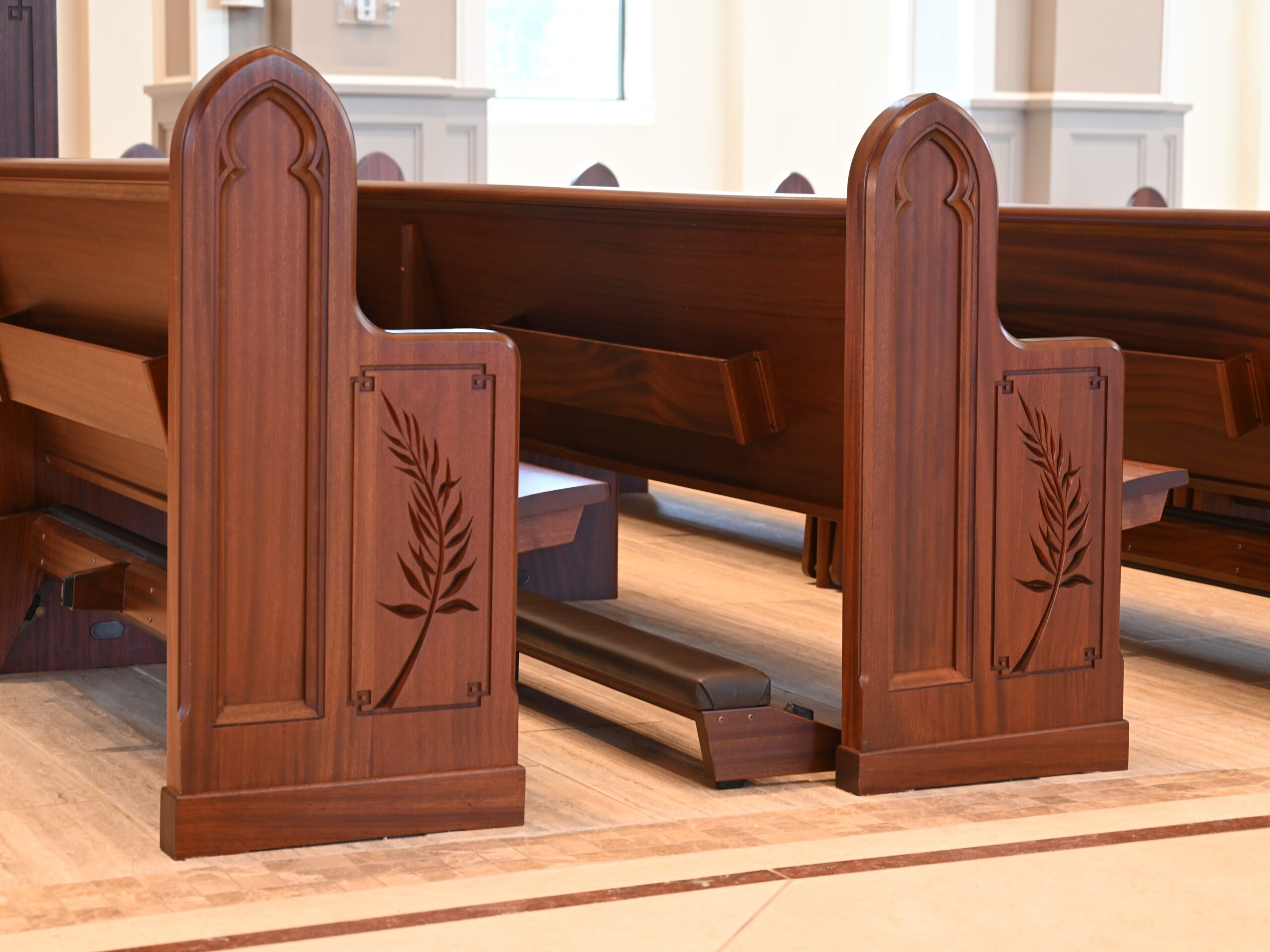 Pew ends with simple wheat engravings and black kneelers.