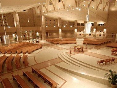 A high-angle view of a congregation hall with a wide half-circle of wooden pews